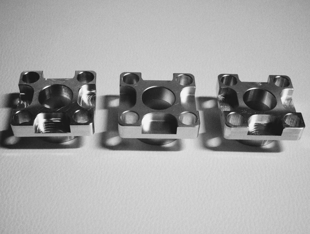 Three machined aluminum blocks with pockets and bores