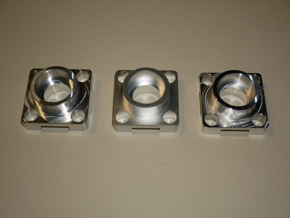 Three machined flanged housings with bored centers and mounting holes